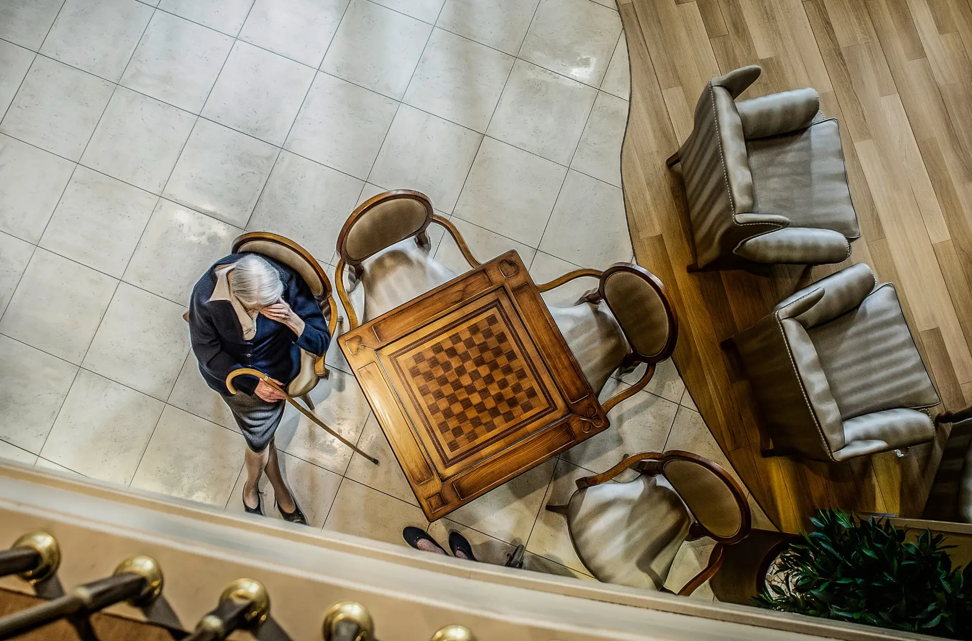 Une femme âgée assise près d’une table de jeu, photographiée en plongée par Didier Carluccio